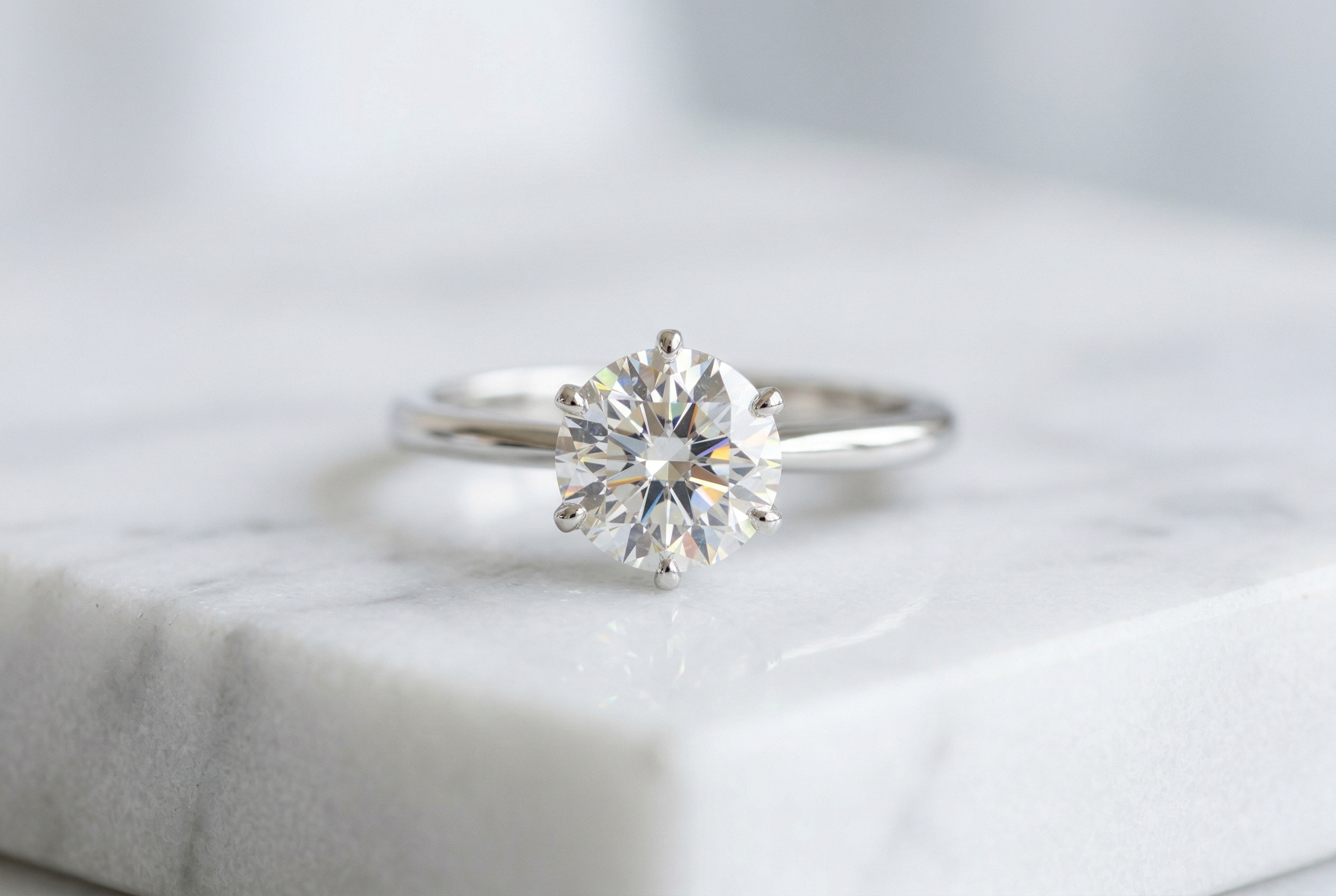 Lab grown diamond solitaire engagement ring on white marble